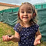 child, girl, snail, outdoor, grass, fence, dress, heart_pattern, bracelet, necklace, smile, happy, curly_hair, nature, daylight, playing, person, young, face, cute