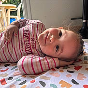 Yléana a rejoint le concours — aidez-le/la à gagner de superbes lots ! toddler, child, smiling, striped_shirt, patterned_blanket, indoor, floor_tiles, hand_on_head, playful, relaxed_pose, colorful, person, young_child, casual, home, happy, face, portrait, clothing, nail_polish