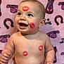 baby, child, smiling, lipstick_marks, face, skin, arms, torso, blanket, pink_background, patterned_blanket, happy, cute, infant, seated, expression, playful, red, lips, portrait