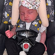 Nathania is registered to the contest to win money with this photo: baby, sleeping, car_seat, headwrap, floral_pattern, white_socks, black_pants, safety_harness, infant, peaceful, cute, child, indoor, soft_toys, blanket, comfort, rest, toddler, young_child, portrait