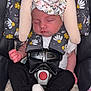 baby, sleeping, car_seat, headwrap, floral_pattern, white_socks, black_pants, safety_harness, infant, peaceful, cute, child, indoor, soft_toys, blanket, comfort, rest, toddler, young_child, portrait