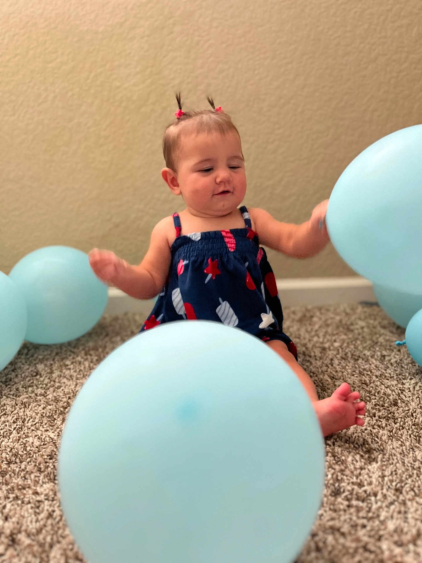 Nathania joined the competition — help win amazing prizes! baby, child, balloon, blue, carpet, indoor, person, cute, dress, pigtails, infant, sitting, playful, happy, room, wall, foot, small_person, celebration, fun