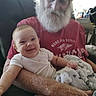 Silas is registered to the contest to win money with this photo: baby, infant, grandfather, elderly_man, beard, smiling, portrait, sitting, holding, blanket, white_shirt, red_shirt, baseball_cap, armchair, indoor, family, cuddling, happy, closeup, photography