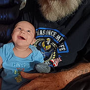Silas is registered to the contest to win money with this photo: baby, infant, child, smiling, happy, portrait, indoor, adult, grandparent, beard, arms, cuddle, blue_clothing, onesie, leather_chair, seated, closeup, family, photograph, casual