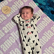 Amelia joined the competition — help win amazing prizes! baby, infant, four_months, onesie, hearts, pink_bows, blanket, personalized_blanket, name, wooden_plaque, milestone, lying_down, cute, smiling, face, person, child, relaxed, indoor, soft_texture