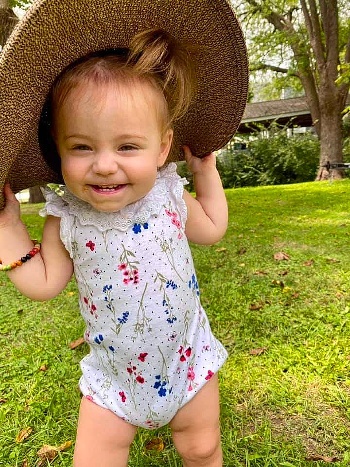 Molly is registered to the contest to win money with this photo: baby_toddler_clothing, eye, green, hair, hairstyle, happy, hat, head, human_body, iris, joy, leaf, nose, people_in_nature, person, plant, skin, sleeve, smile, standing