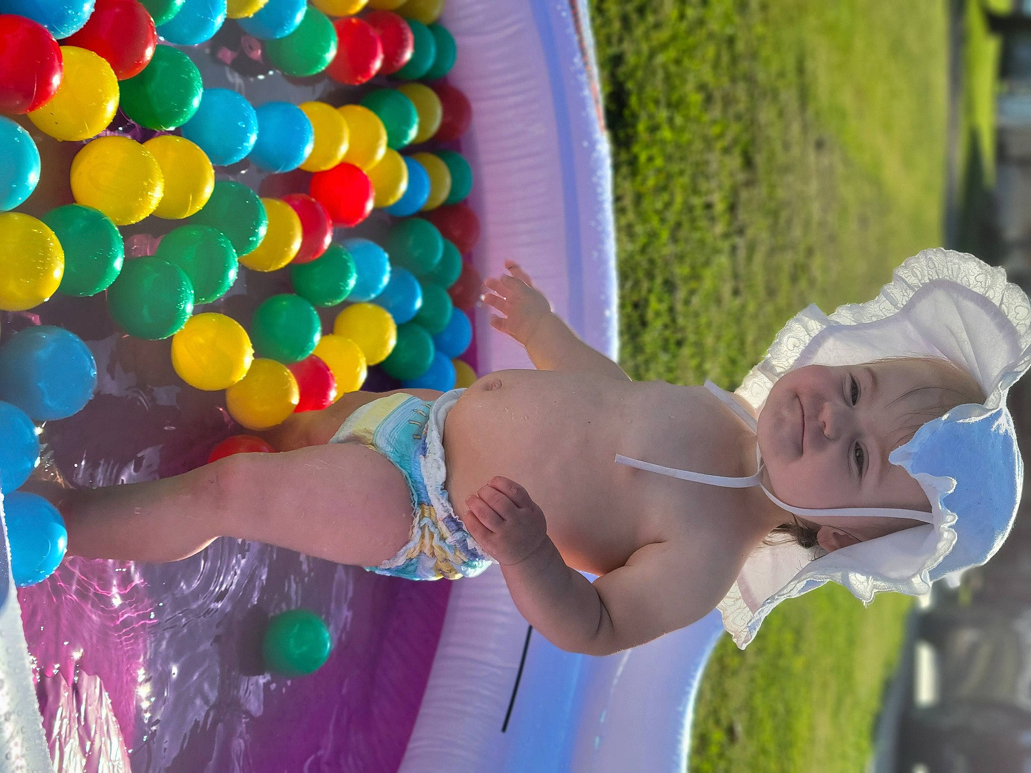 Molly is registered to the contest to win money with this photo: balloon, child, event, fun, grass, happy, hat, headwear, human_leg, leisure, light, party, party_supply, person, recreation, smile, swimwear, thigh, toddler, toy