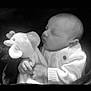 baby, newborn, sleeping, plush_toy, giraffe_toy, white_sweater, blanket, infant, child, peaceful, soft_texture, closeup, portrait, cuddly, cute, resting, hand, warm, monochrome, cozy