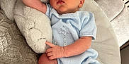 Oakley is registered to the contest to win money with this photo: baby, newborn, sleeping, blue_clothing, knitwear, socks, plush_toy, stuffed_animal, couch, blanket, cozy, infant, child, indoors, resting, soft_texture, cute, peaceful, person, portrait