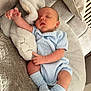 baby, newborn, sleeping, blue_clothing, knitwear, socks, plush_toy, stuffed_animal, couch, blanket, cozy, infant, child, indoors, resting, soft_texture, cute, peaceful, person, portrait