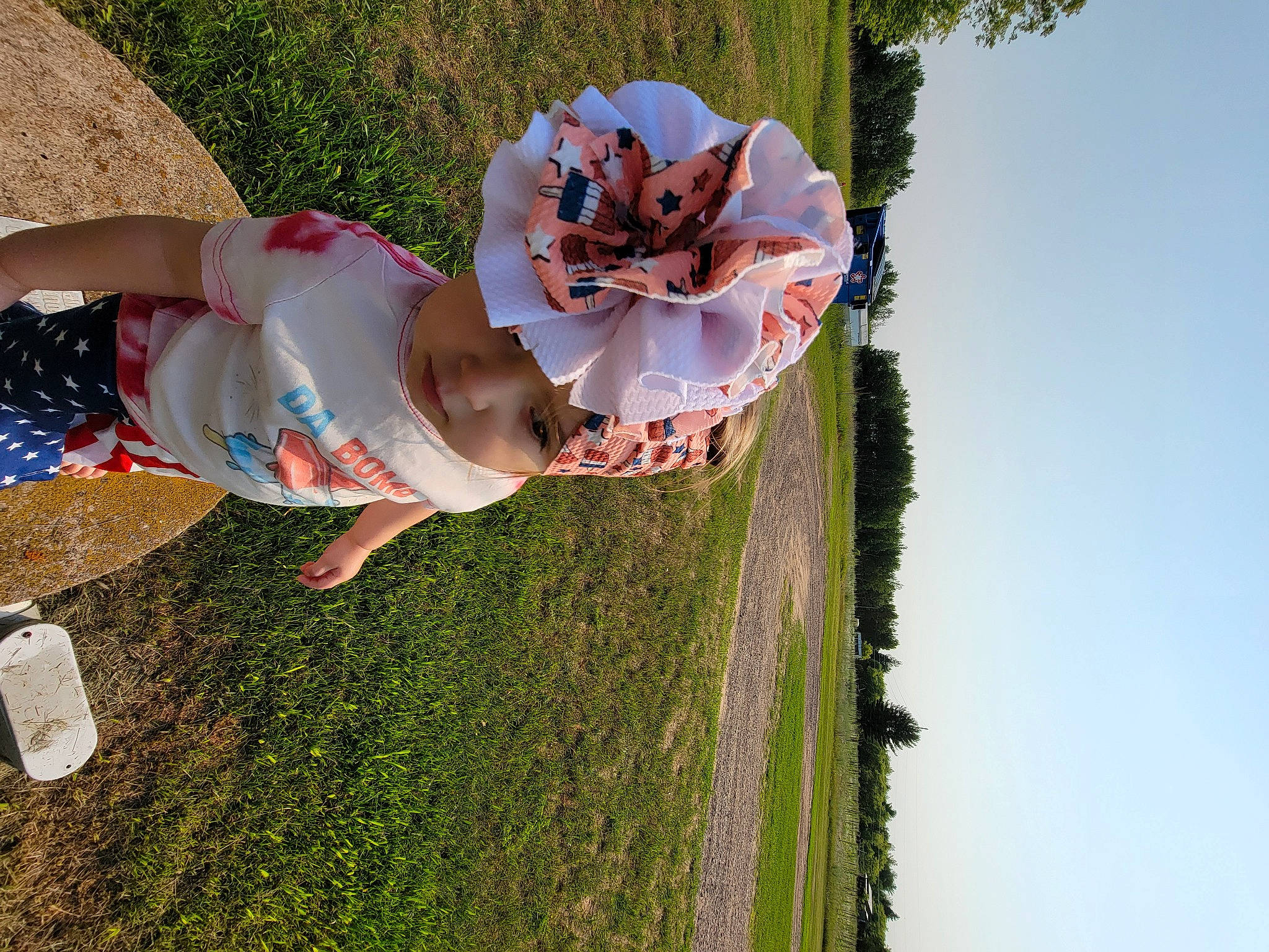 Raylynn is registered to the contest to win money with this photo: child, dress, fun, grass, happy, hat, headwear, human_leg, landscape, lawn, leisure, people_in_nature, person, petal, plant, pole, recreation, sky, thigh, toddler