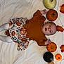 baby, infant, pumpkins, fall_leaves, autumn, white_sheet, decorations, orange, black_pumpkin, clothing, tights, smiling, festive, holiday, seasonal, cute, lying_down, child, portrait, indoor