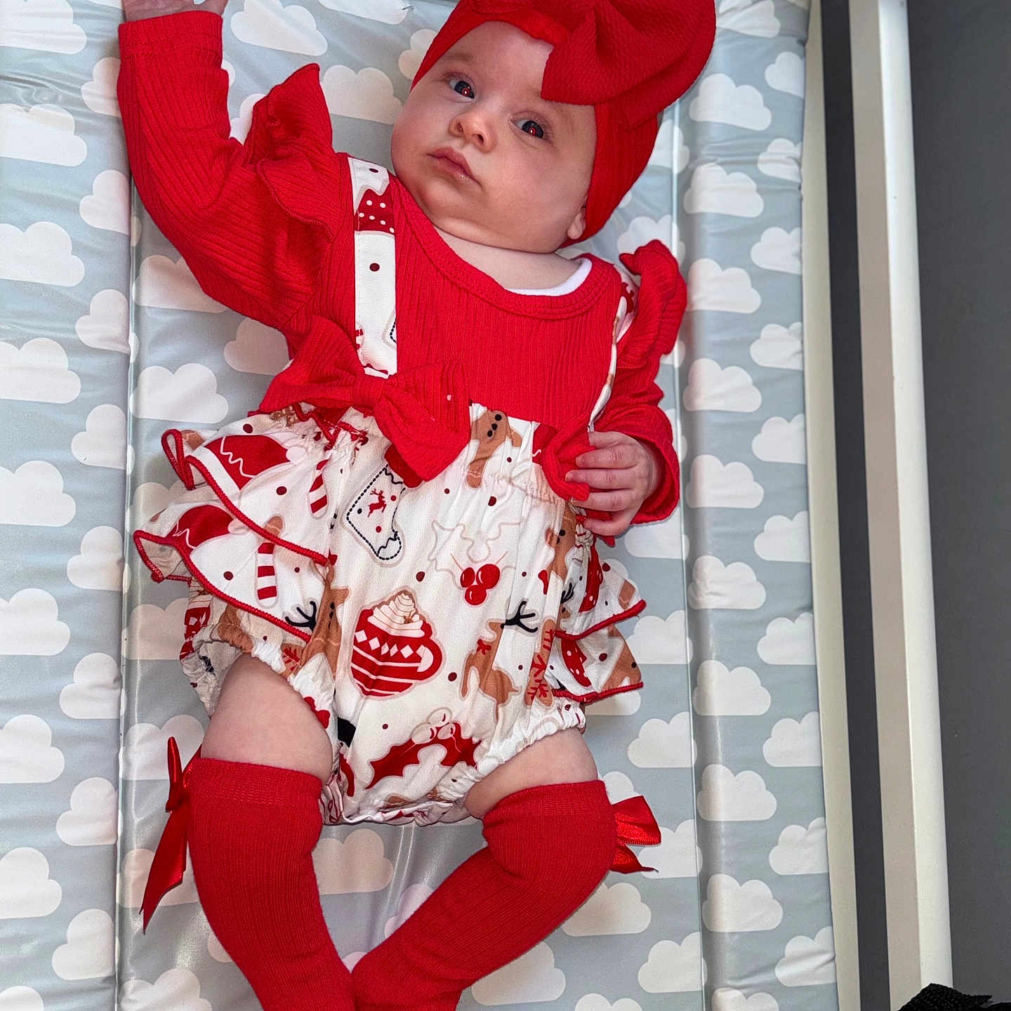 Dulcie-Mae joined the competition — help win amazing prizes! arms, baby, bow, changing_pad, child, cloud_pattern, cozy, cute, expression, face, headband, holiday_theme, indoors, infant, knee_socks, legs, lying_down, patterned_clothing, red_clothing, soft_lighting