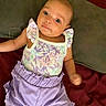 baby, infant, child, blue_eyes, pastel_clothing, floral_top, lavender_shorts, ruffles, lying_down, soft_surface, curious_look, cute, portrait, indoors, person, smiling, baby_clothes, head, arm, legs