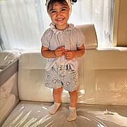 Jade a rejoint le concours — aidez-le/la à gagner de superbes lots ! child, girl, smile, headband, shorts, couch, indoor, window, light, happy, standing, clothing, plastic_cover, sock, person, portrait, cute, home, furniture, casual