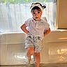 Jade a rejoint le concours — aidez-le/la à gagner de superbes lots ! toddler, child, blouse, denim_shorts, headband, bow, couch, window, indoor, natural_light, curly_hair, socks, standing, confident, portrait, casual_clothing, home, cute, fashion, smile