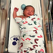 Dakota joined the competition — help win amazing prizes! newborn, baby, swaddled, blanket, footprint_pattern, hospital_bassinet, sleeping, infant, wrapped, peaceful, child, healthcare, bed, mattress, person, cute, small, resting, indoors, soft_lighting