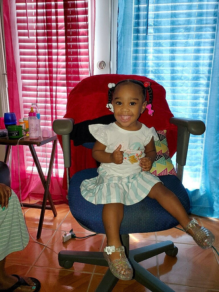 K Lei is registered to the contest to win money with this photo: baby_toddler_clothing, chair, curtain, embellishment, event, fun, furniture, happy, human_leg, joy, magenta, person, pink, purple, sandal, smile, sock, thigh, toddler, watch