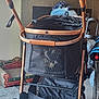 dog, pet_stroller, mesh, indoor, carpet, blanket, wheel, decor, christmas, furniture, pet, cage, resting, small_dog, canine, black_mesh, brown_frame, soft_lighting, home, comfort