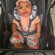 Kaylee joined the competition — help win amazing prizes! baby, child, stroller, headband, pink, floral, clothing, smiling, happy, infant, seatbelt, sitting, indoors, person, cute, face, portrait, toddler, fabric, comfort