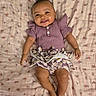 baby, child, smiling, purple_clothing, floral_pattern, blanket, cute, infant, happy, portrait, lying_down, bow, face, skin, person, small_child, indoors, clothing, legs, hands