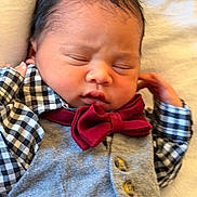 Norwen is registered to the contest to win money with this photo: baby, infant, sleeping, face, clothing, bow_tie, vest, shirt, hand, newborn, cute, portrait, child, soft, blanket, resting, peaceful, indoors, person, young