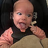 baby, infant, face, tongue_out, car_seat, blanket, pink_clothing, expression, finger, cute, child, person, seatbelt, head, indoors, mischievous, wide_eyes, human, portrait, cozy