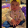 baby, infant, face, headband, yellow_headband, dress, buttons, hands, bed, pillow, blanket, bedding, room, portrait, cute, sitting, eyes, cheeks, indoors, child