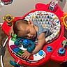 baby, infant, sleeping, nap, child, portrait, face, closed_eyes, activity_center, play_center, toys, colorful, red, indoor, home, nursery, wood_floor, seated, peaceful, candid