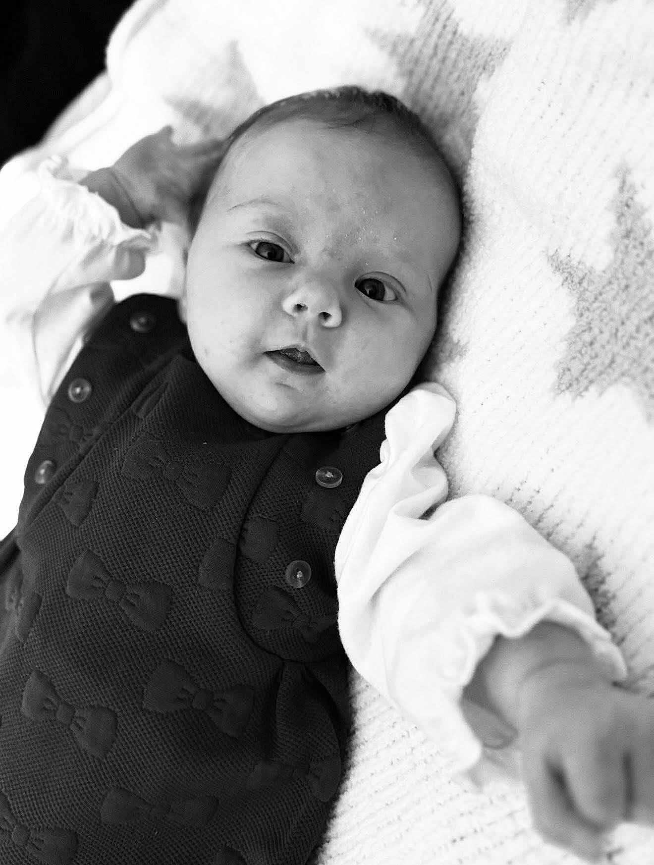 Maggie joined the competition — help win amazing prizes! baby, infant, black_and_white, portrait, clothing, bow_pattern, blanket, texture, cute, face, eyes, hand, lying_down, soft_light, monochrome, child, newborn, person, expression, closeup