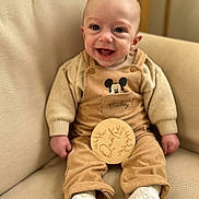 Nino a rejoint le concours — aidez-le/la à gagner de superbes lots ! baby, child, clothing, corduroy, couch, cozy, cute, face, feet, hands, happy, indoors, infant, mickey_mouse, overalls, portrait, sitting, smiling, white_shoes, young