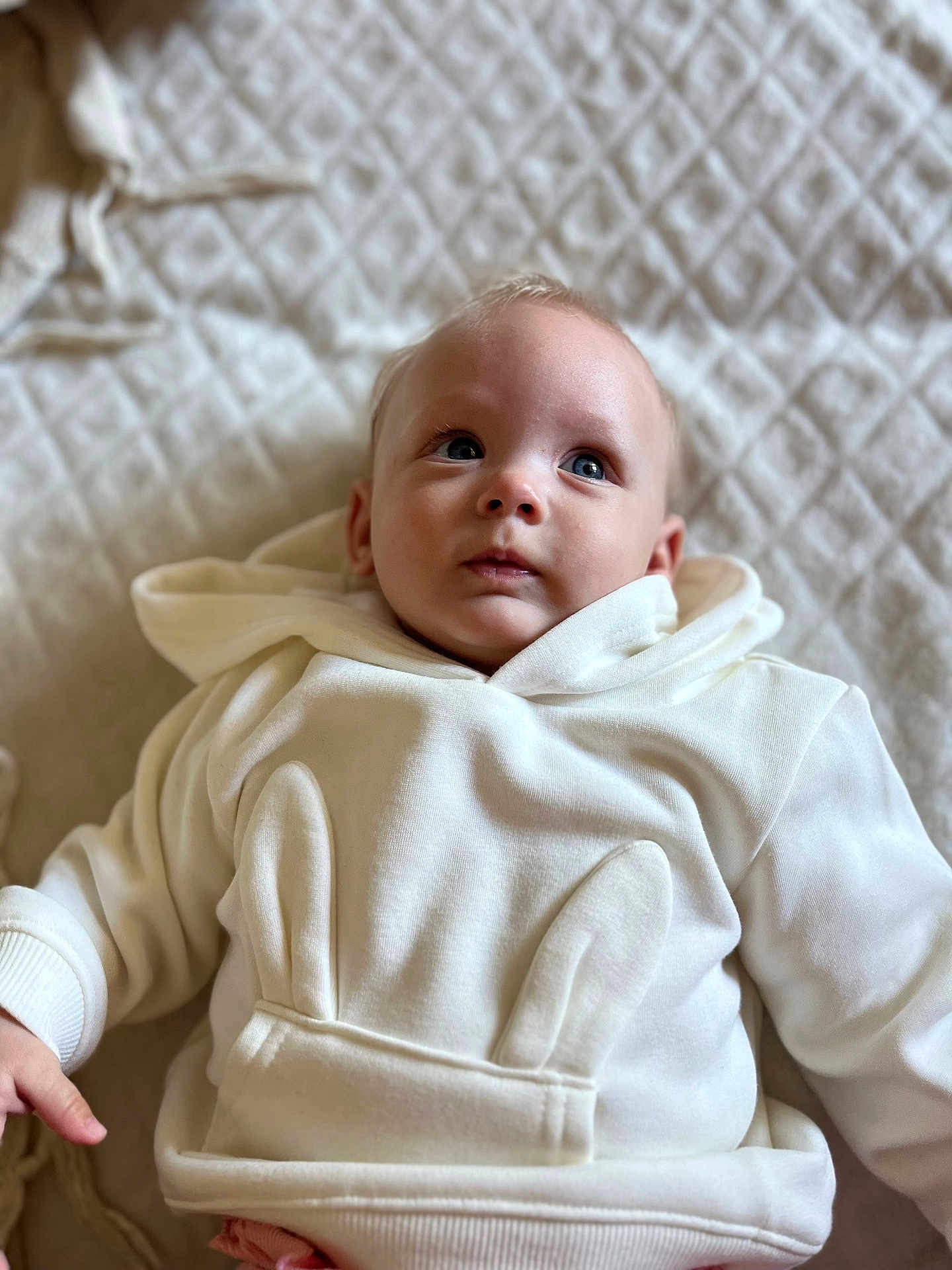 April participe au concours pour gagner de l'argent avec cette photo : baby, child, infant, hoodie, white_clothing, bunny_ears, blanket, soft_texture, blue_eyes, cute, portrait, lying_down, indoors, cozy, young_child, face, expression, casual_clothing, warm, comfortable