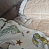 cat, gray_cat, sleeping, lying_down, pet, animal, indoors, couch, quilt, blanket, cozy, nap, relaxed, home, furniture, soft, dinosaur_pattern, stars, portrait, snuggling