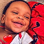 baby, smiling, face, red_blanket, cozy, happy, infant, closeup, cute, child, indoors, sleepwear, soft_texture, dimples, portrait, relaxing, toddler, earring, skin, comfort