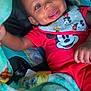 baby, smiling, mickey_mouse, red_clothing, blanket, cartoon_characters, infant, happy, face, child, cute, playful, indoors, soft_texture, closeup, portrait, hand, seat, comfort, wrapped