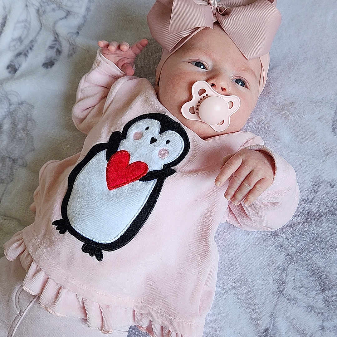 Giulyana participe au concours pour gagner de l'argent avec cette photo : adorable, baby, baby_girl, blanket, bow, child, comfort, cozy, cute, headband, indoors, infant, lying_down, newborn, pacifier, penguin_design, pink_clothing, portrait, sleepwear, soft_toys
