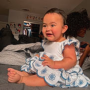 Ocean is registered to the contest to win money with this photo: baby, bed, blanket, child, clothing, curly_hair, cute, dress, face, family, foot, hand, happy, indoor, person, portrait, room, sitting, smile, young_child