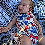 Clover is registered to the contest to win money with this photo: baby, infant, smiling, dress, patterned_clothing, red_bow, blue_bow, blanket, black_and_white, laying_down, happy, outdoor, sunlight, shadow, cute, child, person, skin, cheerful, young