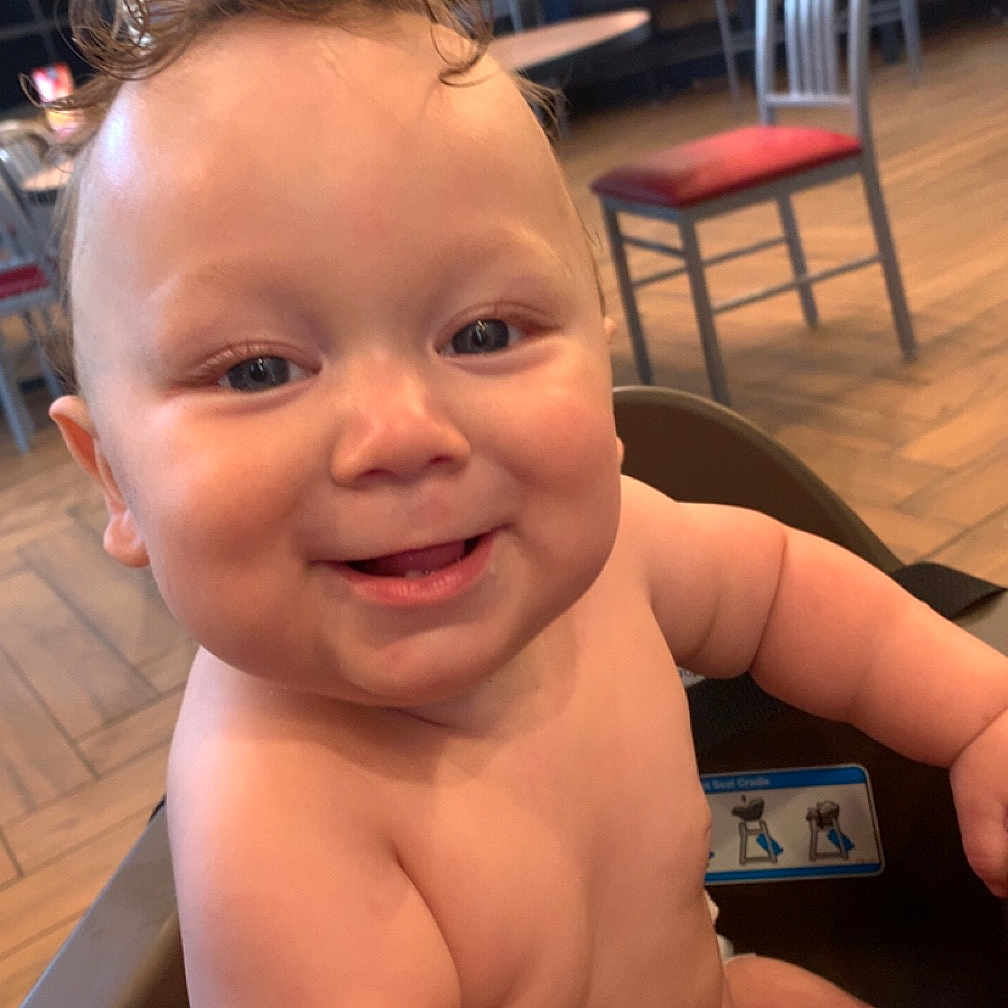 Miguel is registered to the contest to win money with this photo: adult, baby, chair, cutlery, face, furniture, happy, hardwood, head, indoors, male, man, person, photography, portrait, restaurant, sitting, smile, table, wood