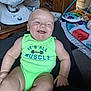 baby, infant, smiling, green_onesie, muscle_text, indoor, toy, baby_gear, wooden_furniture, playmat, happy, child, skin, face, arm, leg, sitting, cute, chubby, expression