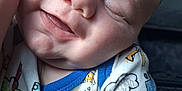 Riven is registered to the contest to win money with this photo: baby, sleeping, close_up, onesie, child, infant, smile, hand, face, cheek, clothing, cute, peaceful, resting, skin, person, young, indoors, comfort, doodle_print