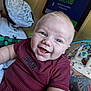 Riven is registered to the contest to win money with this photo: baby, smiling, blue_eyes, red_shirt, striped_clothing, tattoo, arm, baby_seat, television, indoor, happy, person, child, closeup, infant, skin, face, mouth_open, cheeks, cute