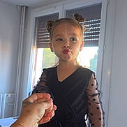 Miléna participe au concours pour gagner de l'argent avec cette photo : child, girl, black_clothing, polka_dot, sheer_sleeves, indoor, window, hand_holding, pout, cute, fashion, portrait, sunlight, hair_buns, smile, person, home, casual, young, playful