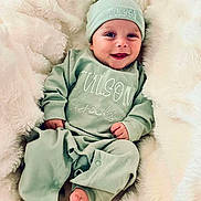 Tulson is registered to the contest to win money with this photo: baby, smiling, infant, pajamas, hat, blanket, soft, cozy, cute, lying_down, happy, child, newborn, face, foot, hand, indoors, portrait, apparel, sleepwear