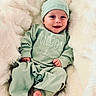 baby, smiling, infant, pajamas, hat, blanket, soft, cozy, cute, lying_down, happy, child, newborn, face, foot, hand, indoors, portrait, apparel, sleepwear