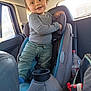 toddler, child, car_seat, vehicle_interior, long_sleeve_shirt, pants, smile, hair, window, water_bottle, shoe, sneaker, seat, car, happy, person, interior, playful, standing, casual