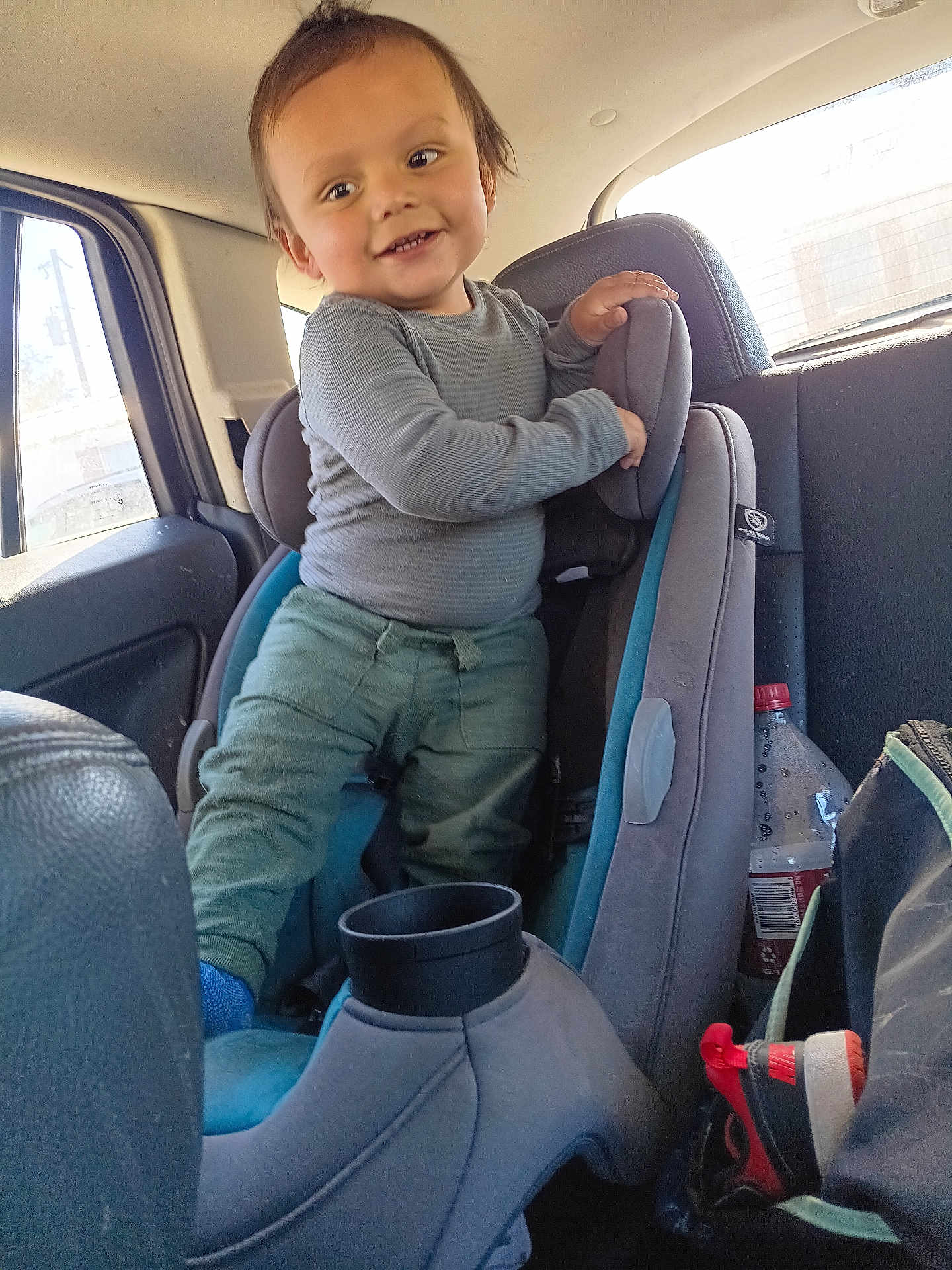 Everett joined the competition — help win amazing prizes! toddler, child, car_seat, vehicle_interior, long_sleeve_shirt, pants, smile, hair, window, water_bottle, shoe, sneaker, seat, car, happy, person, interior, playful, standing, casual