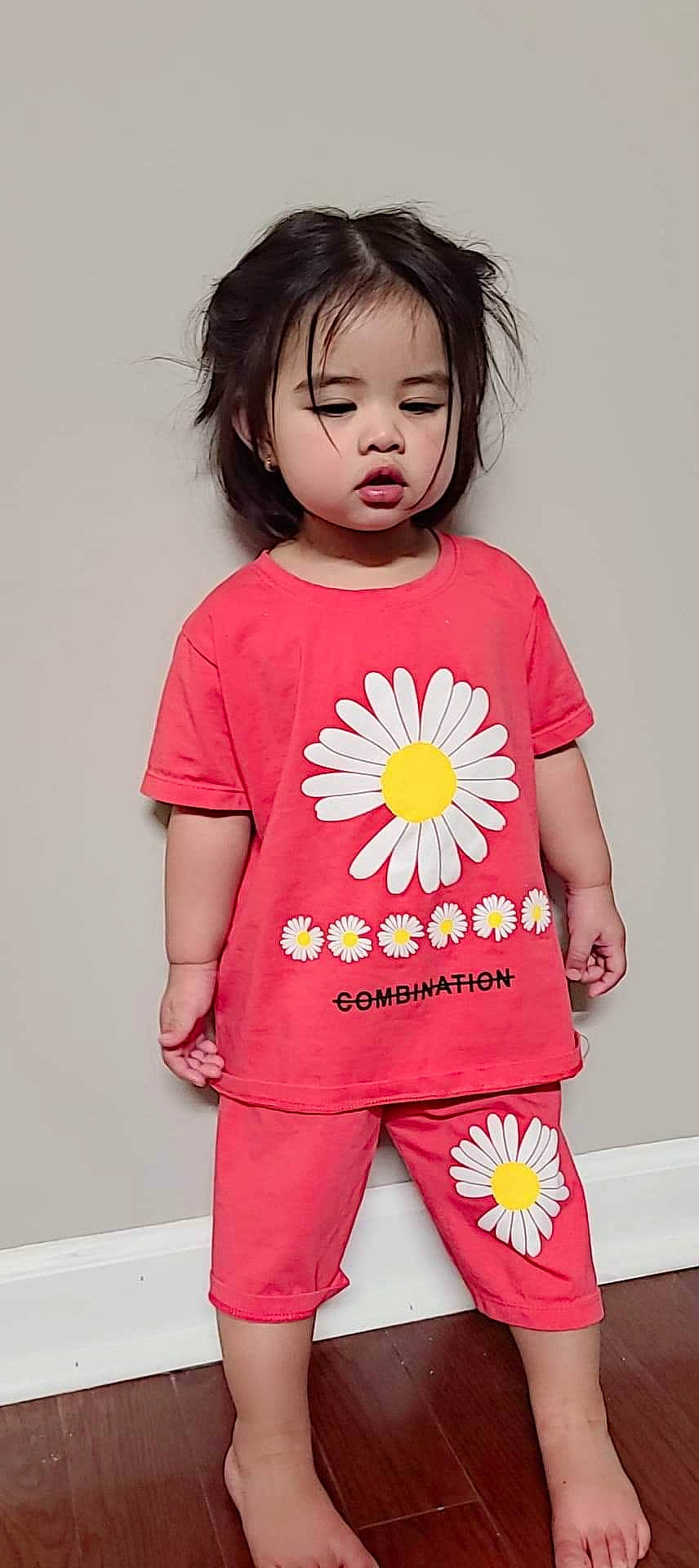 Katie is registered to the contest to win money with this photo: arm, baby_toddler_clothing, dress, eyelash, face, facial_expression, finger, flower, hand, happy, head, human_body, neck, person, pink, plant, skin, sleeve, standing, t_shirt