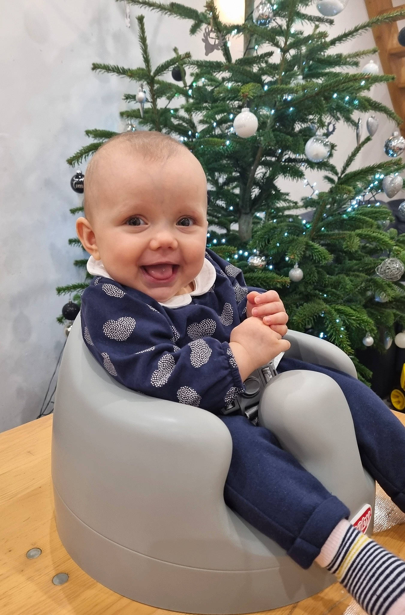 Emma participe au concours pour gagner de l'argent avec cette photo : baby, baby_products, baby_toddler_clothing, child, christmas_ornament, christmas_tree, comfort, conifer, event, fun, hairstyle, happy, joy, lap, leisure, pattern, person, sitting, sleeve, smile