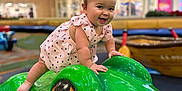 Allison is registered to the contest to win money with this photo: baby, toddler, child, frog, sculpture, playground, indoor_mall, pink_dress, bow, smile, portrait, play, toy, seat, happy, shiny, colorful, depth_of_field, person, fashion